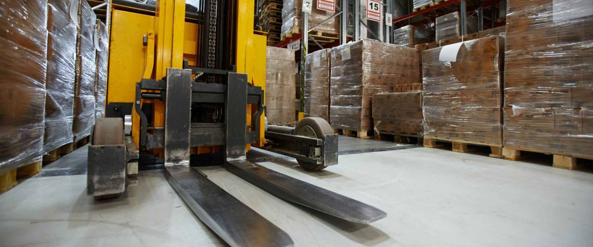 Forklift truck in aisle between storage shelves