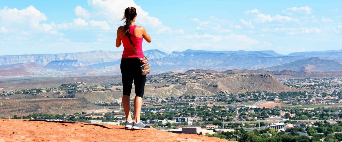 Woman atop the Sugarloaf rock formation overlooking St George, Utah.