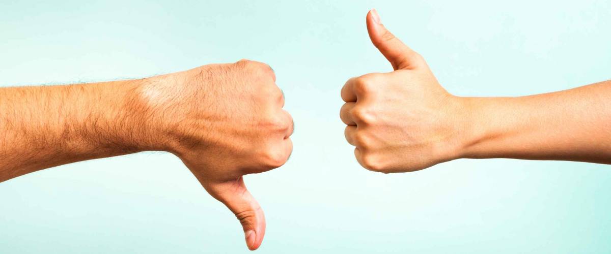 Two hands signalling thumbs up and thumbs down. The smooth hand on the left is making a thumbs up gesture while the hairy hand on the right is making a thumbs down gesture.