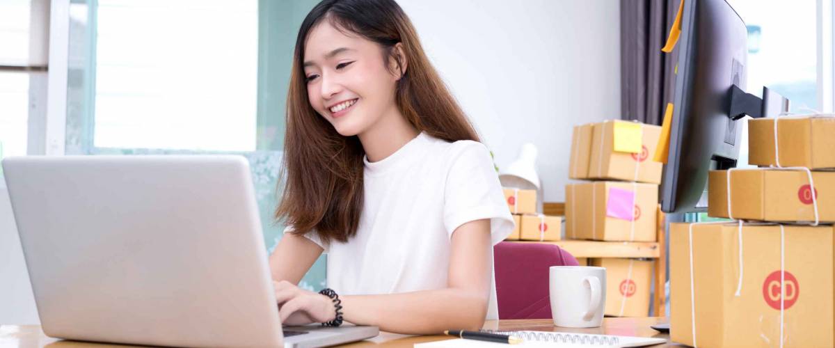 Freelancer woman business private working at office in home interior smile checking order from laptop computer for customer and online delivery for ready packing on working table