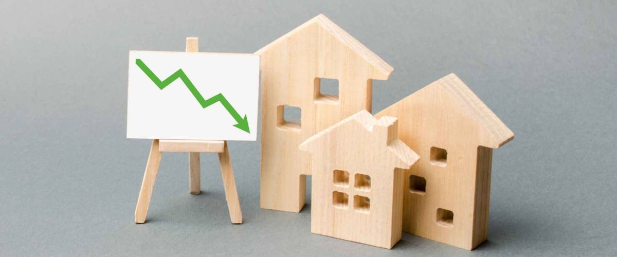 Wooden houses and an easel arrow down represent falling mortgage rates.