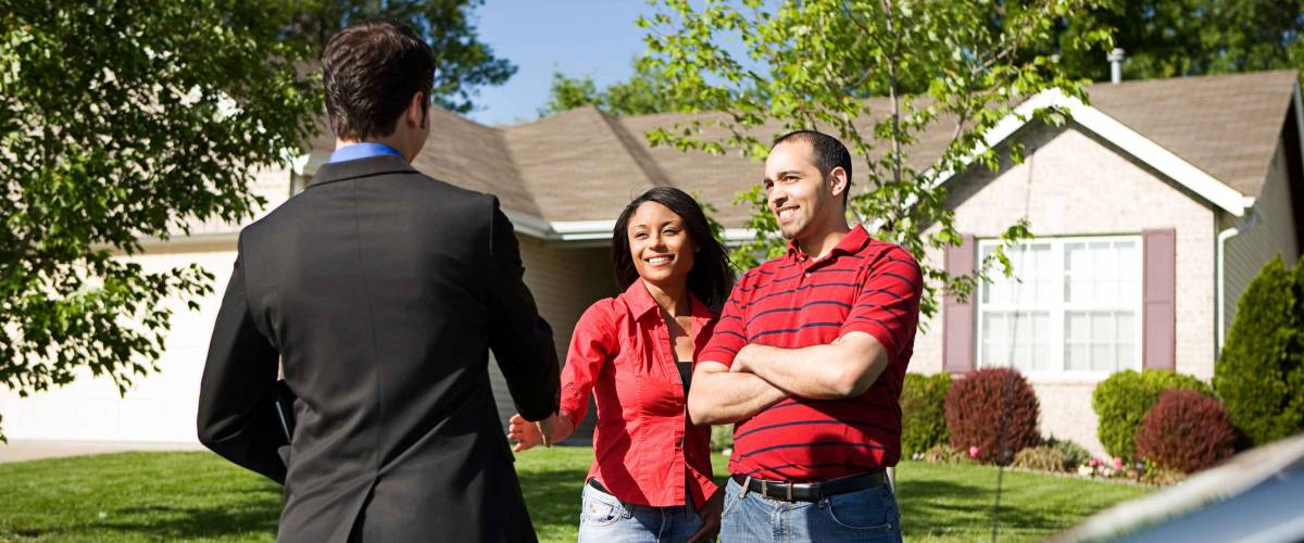 Real Estate Agent and Couple in front of a home.