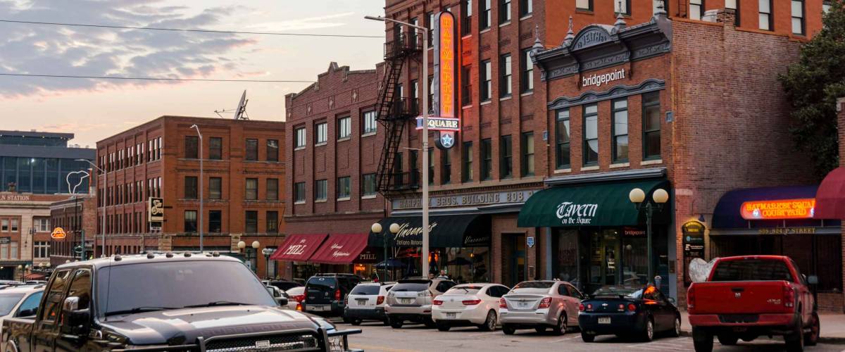 Nebraska, USA - Aug 10, 2017: Brick commercial buildings with preserved historical aesthetic character along P Street in the Haymarket district, Lincoln City. Cars parked along this street.