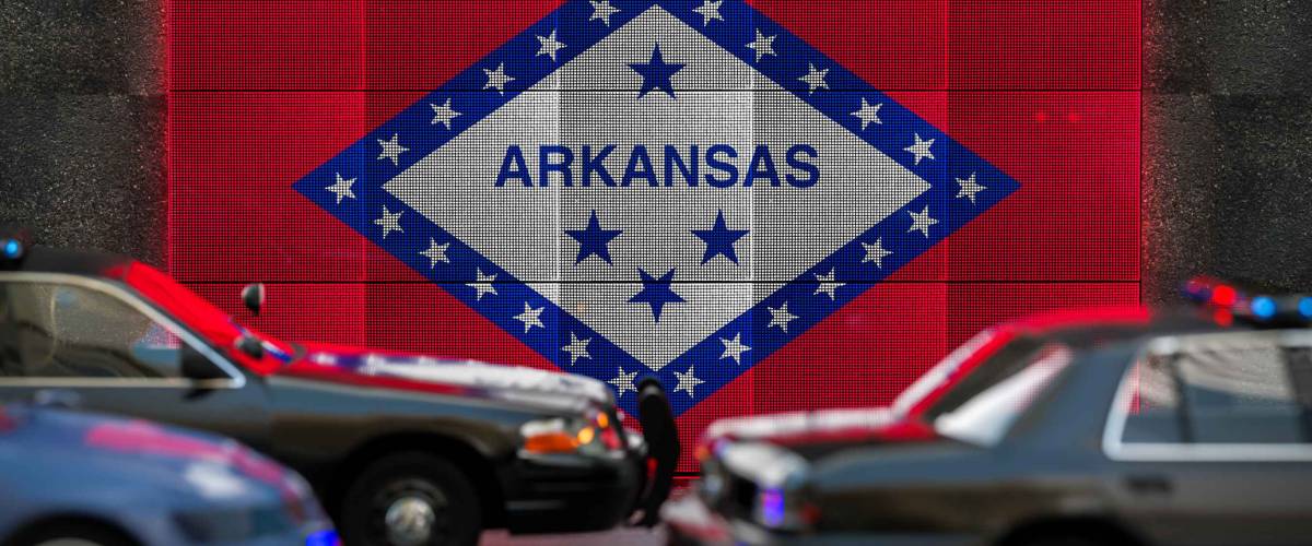 Bright digital display Arkansas flag in city as cars drive past