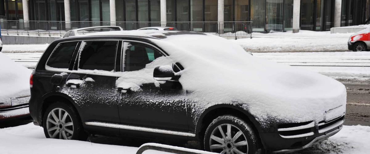 parked cars covered with snow during snowing in winter time