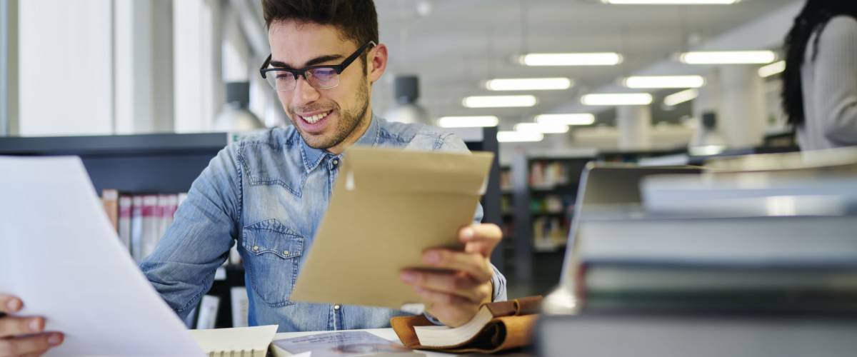 Male journalist with eyeglasses checking written article on blank paper