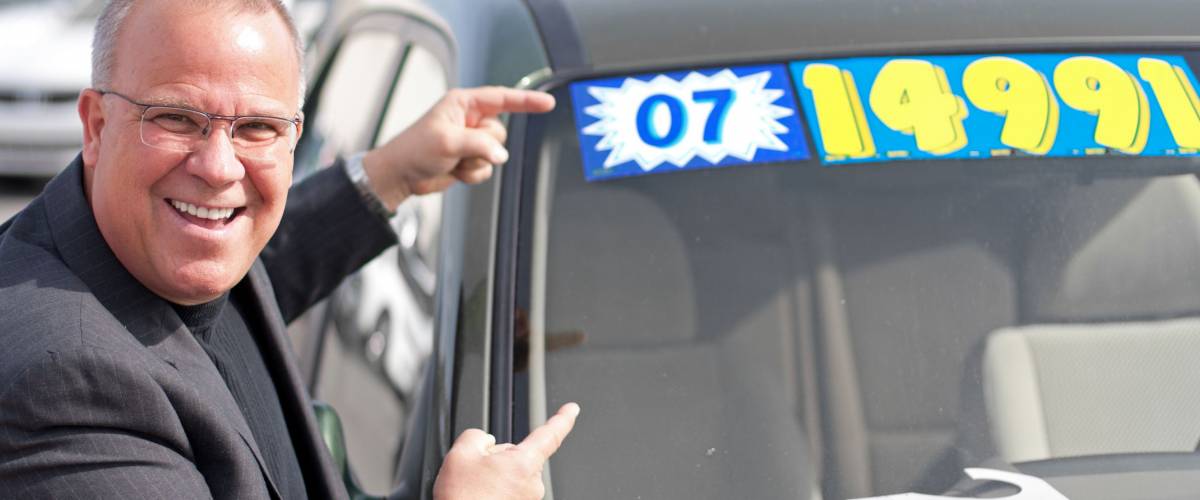 car salesman on lot with price sticker on cae selling