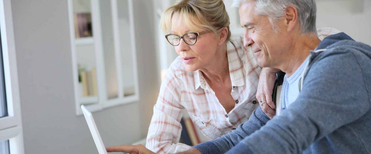 Senior couple at home checking expenses on internet