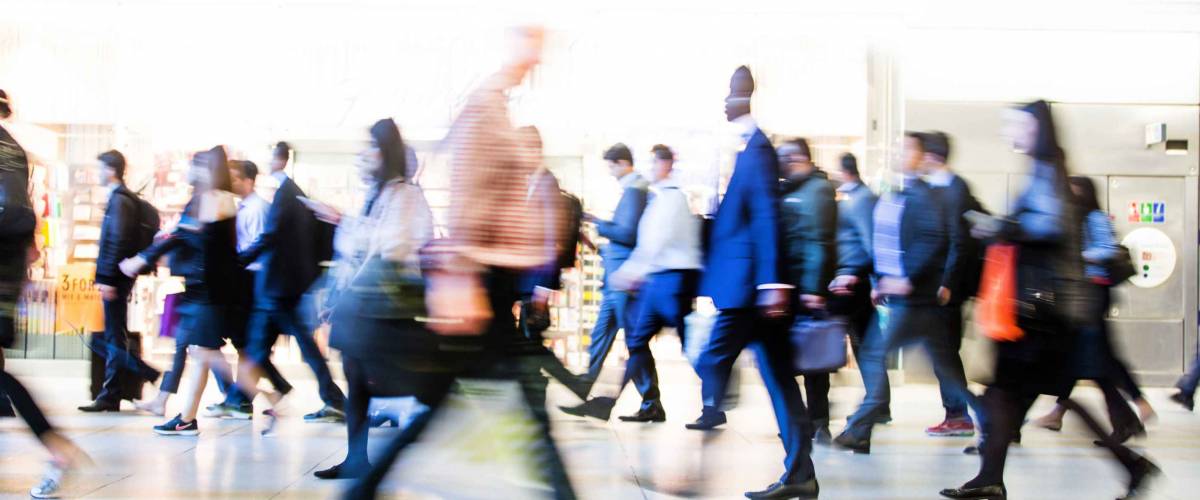 Blur of office workers walking pass the Canary Wharf tube station in early morning rush hours