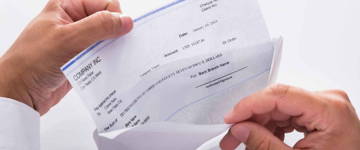 Close-up of a businessman's hand opening envelope with paycheck