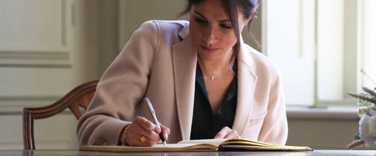 Meghan Duchess of Sussex signing the visitors book during an engagement at Edes House in Chichester