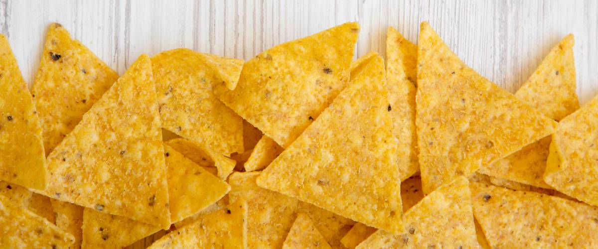 Tortilla chips on white wooden surface, top view. Mexican food.