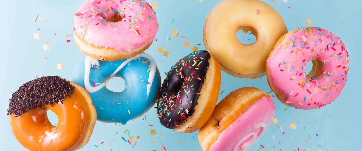 flying doughnuts scene - mix of multicolored sweet donuts with sprinkel on blue background
