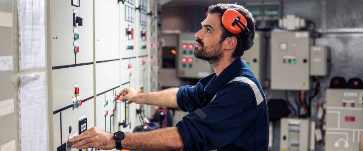 Marine engineer officer in engine control room ECR. Seamen's work. He starts or stops main engine of ship