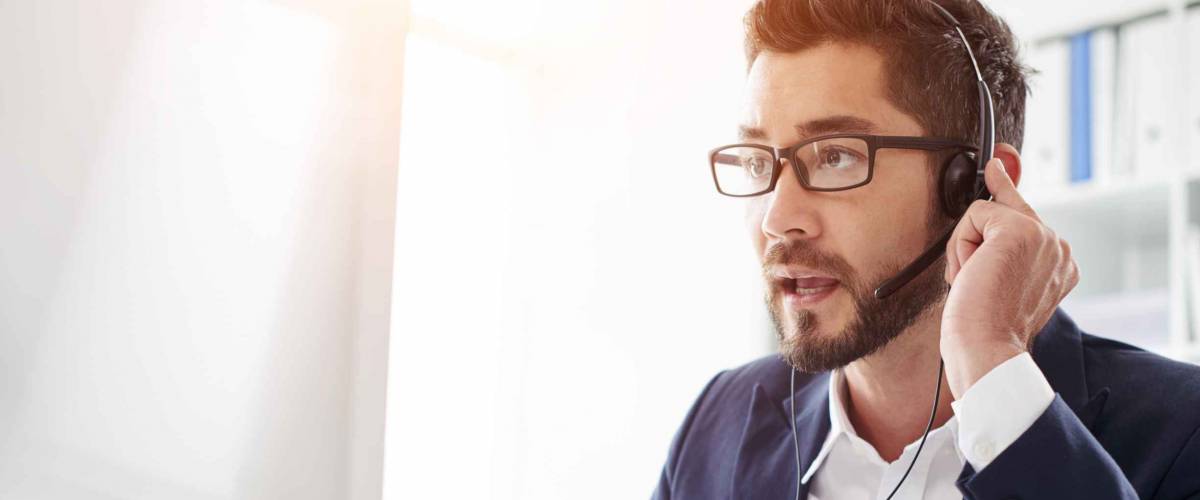 Tech support manager in headset consulting a client