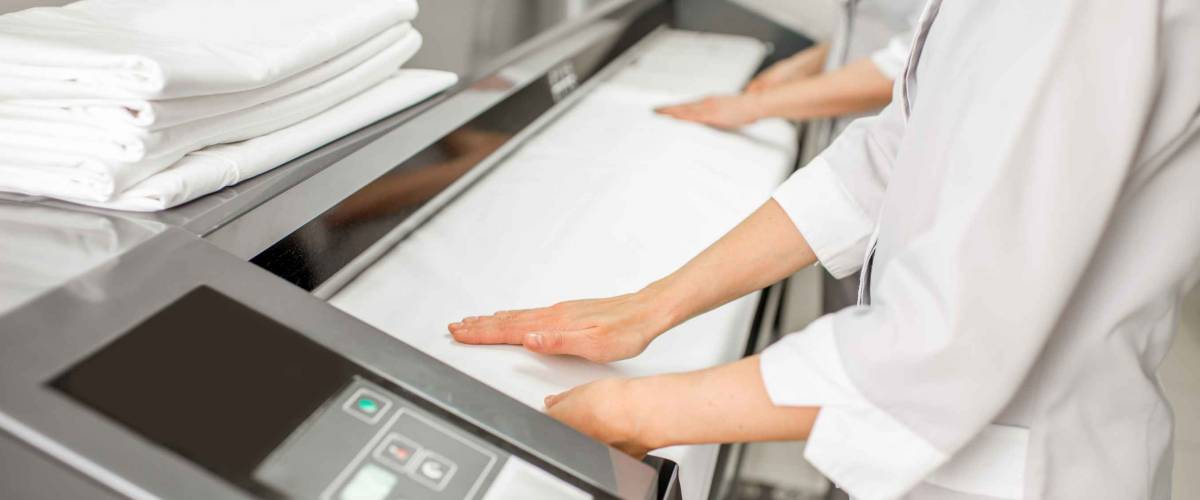 Ironing bedclothes with professional ironing machine in the laundry