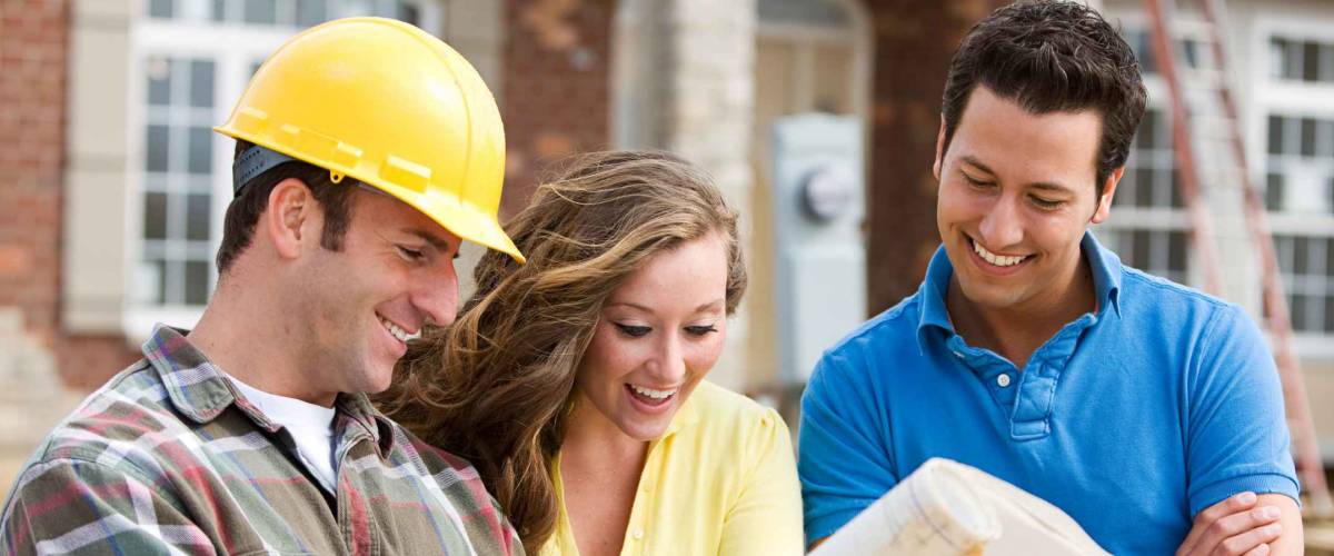 Construction: Young Couple Look At Home Plans with Builder.