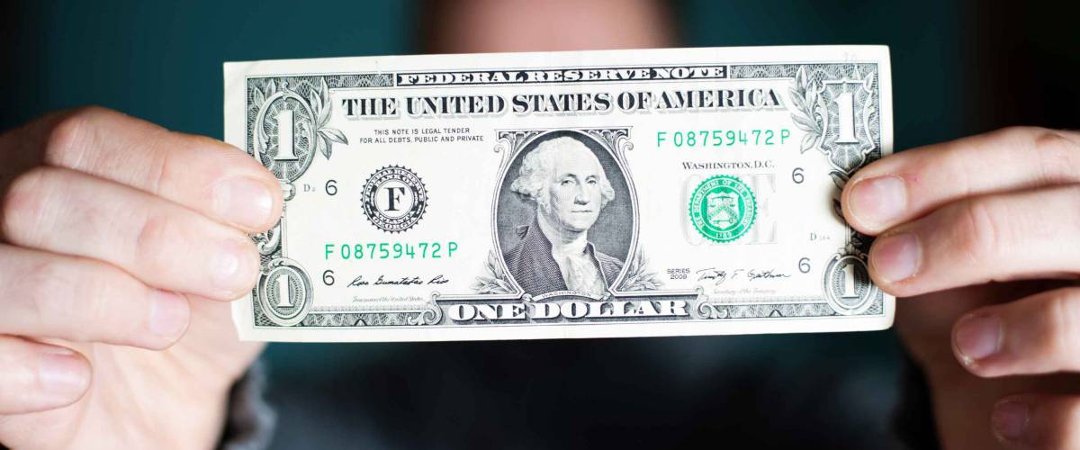 A man holds a U.S. 1 one dollar.