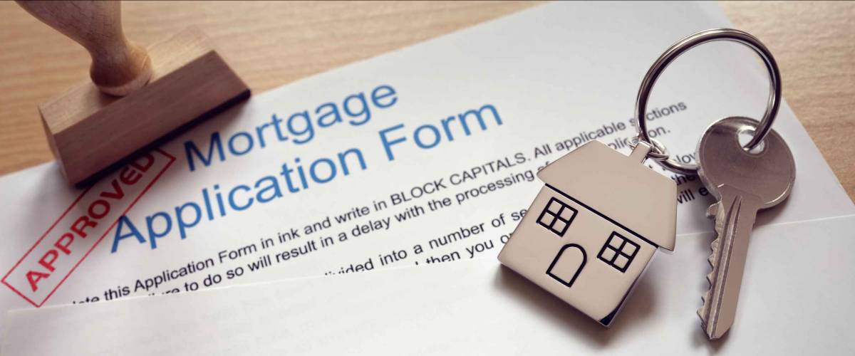 Mortgage loan agreement application with key on house shaped keyring