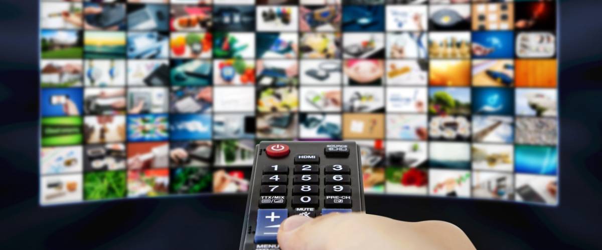 Big LCD panel with television stream images and remote control in hand
