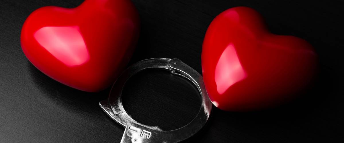 Two red hearts and steel handcuffs on dark background.St Valentine day and Fifty shade of black concept