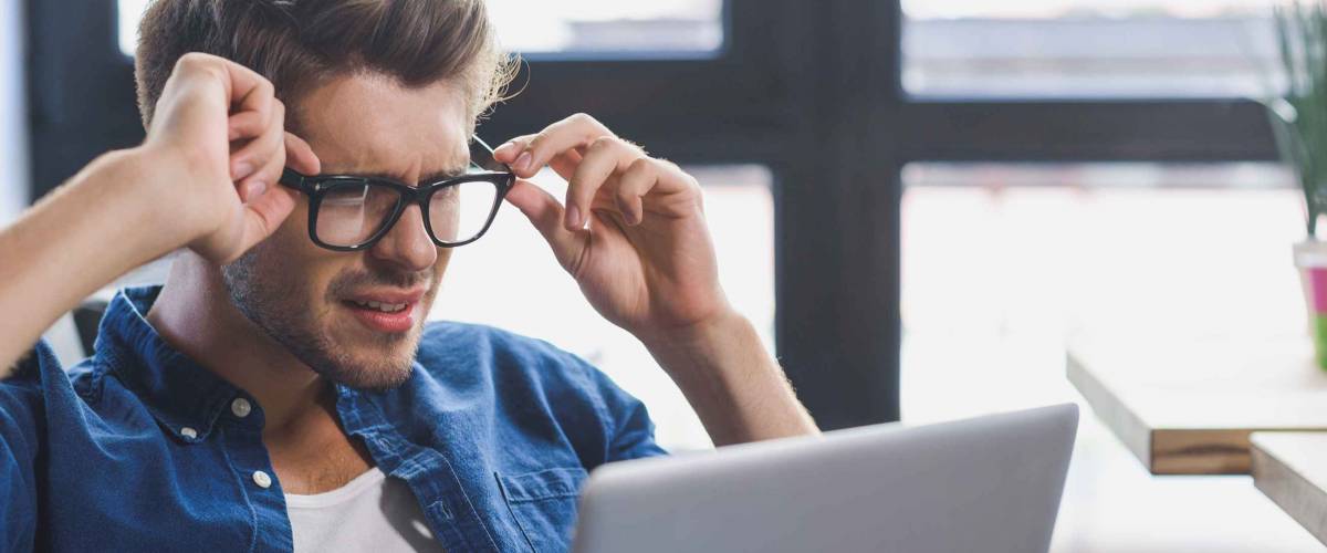 man feeling depressed while looking into laptop
