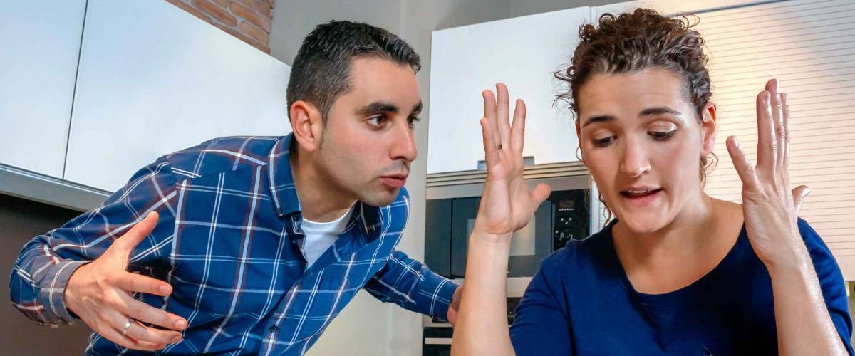 Angry young couple shouting in a hard quarrel by their many debts at home. Financial family problems concept.