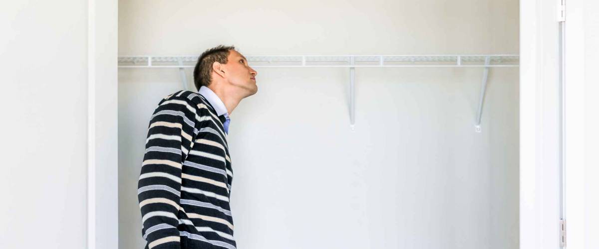 Young man checking looking inside small closet in new room after or before moving in, during open house
