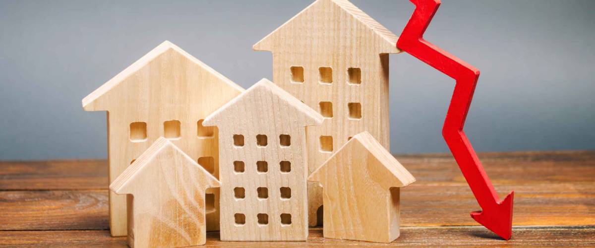 Miniature wooden houses and a red arrow down. The concept of low mortgage rates.