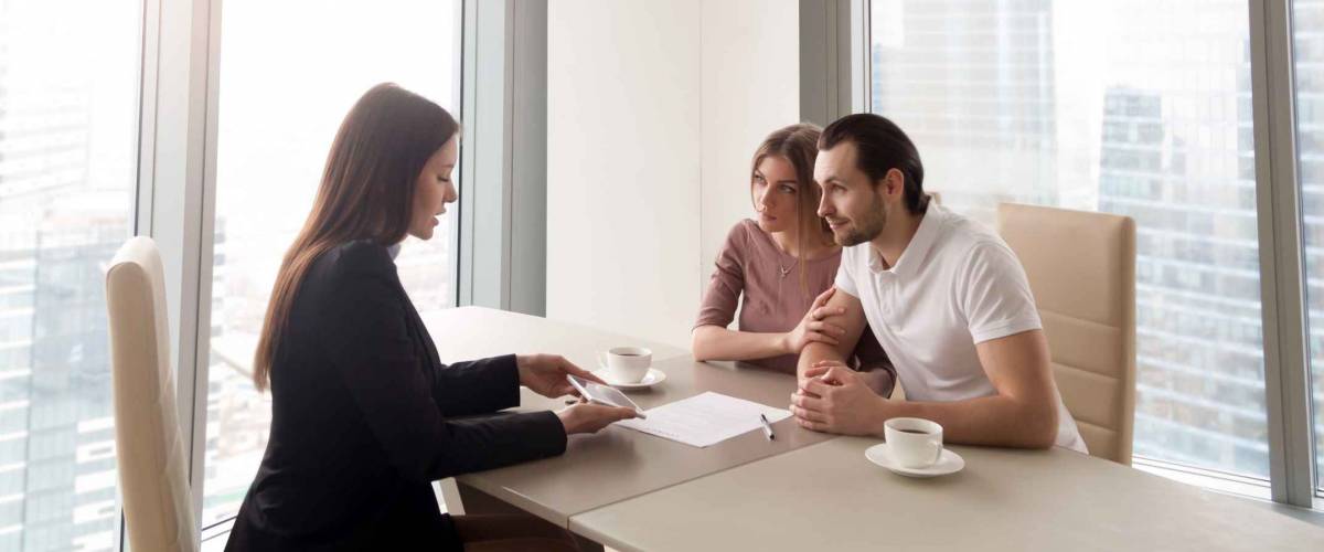 Young family couple meeting with bank worker to sign loan contract, discussing banking credit, personal insurance or mortgage investment, manager showing clients build project on tablet
