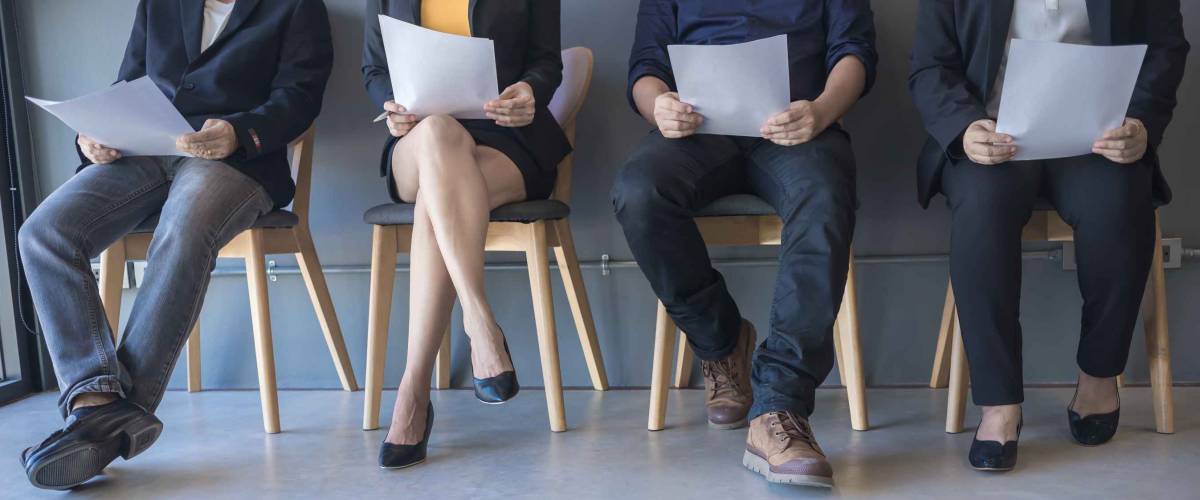 Group of peoples are sitting to review the documents while waiting for a job interview.