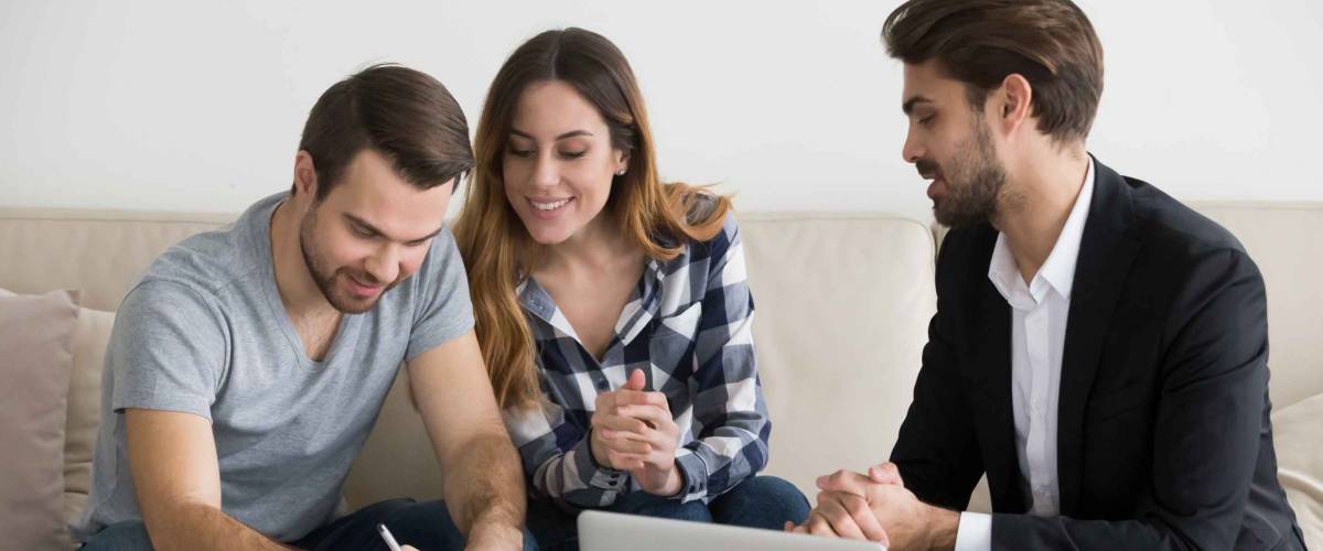 Happy couple signing mortgage loan with lender.