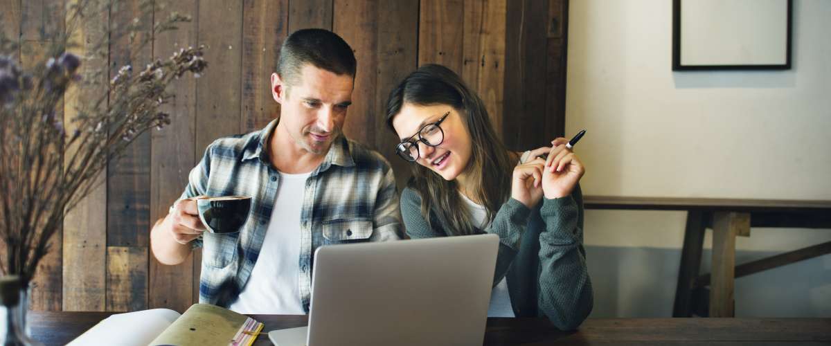 young couple looking over a computer while drinking a coffee