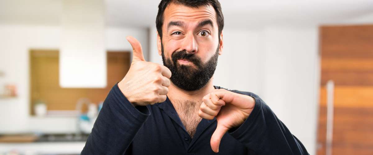 man making good and bad signs while inside a house