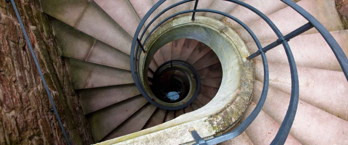 High Angle View of Spiral Staircase Winding Downward in Historical Building, Looking Down at Bottom of Stairs in Elegant Old Building