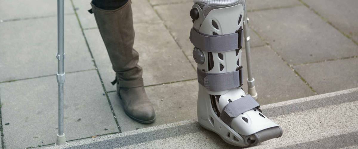 closeup of woman walking with a plaster cast and crutches