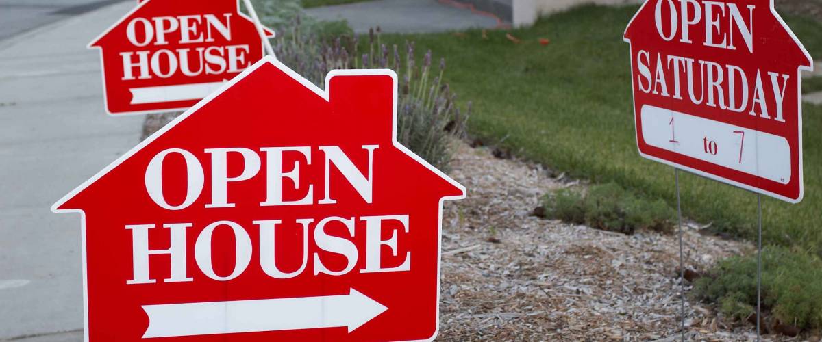 Red and white open house sign close-up with more signs in the background