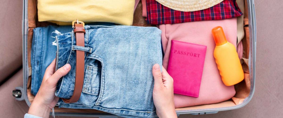 Woman traveler packing clothes in a suitcase