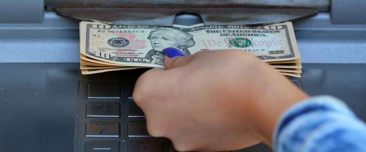woman hand withdrawing money from outdoor bank ATM