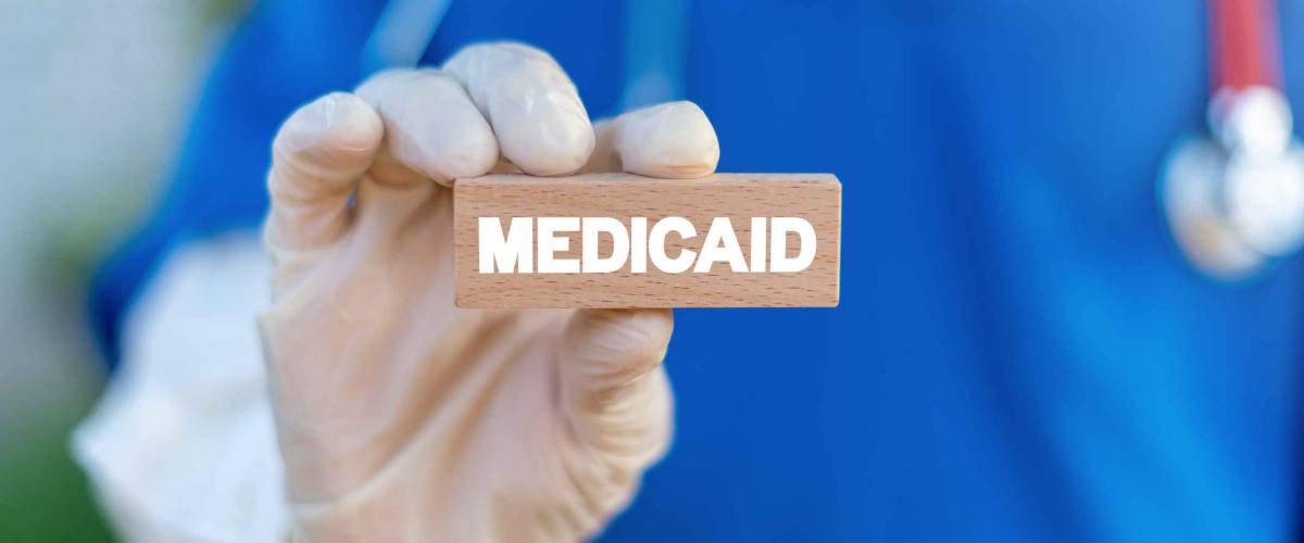 Medicaid written on a wooden block in a doctor's hand