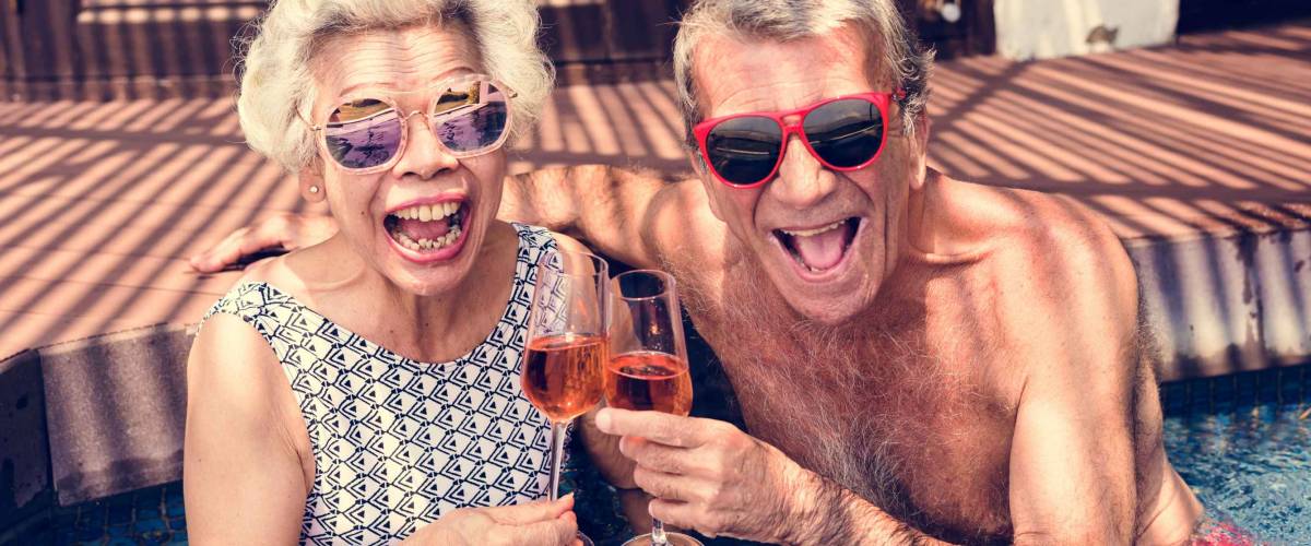Happy seniors drinking prosecco in the pool