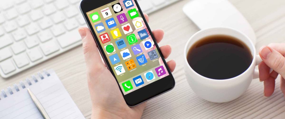 woman hands holding coffee white phone with home screen icons apps and keyboard