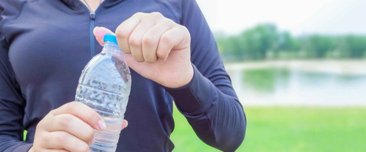 Close-up plastic water bottle in woman hand After Exercise