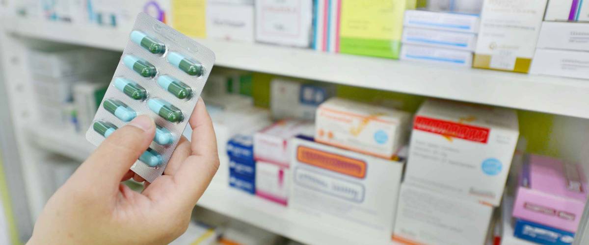 Hand holding medicine capsule pack at the pharmacy drugstore.