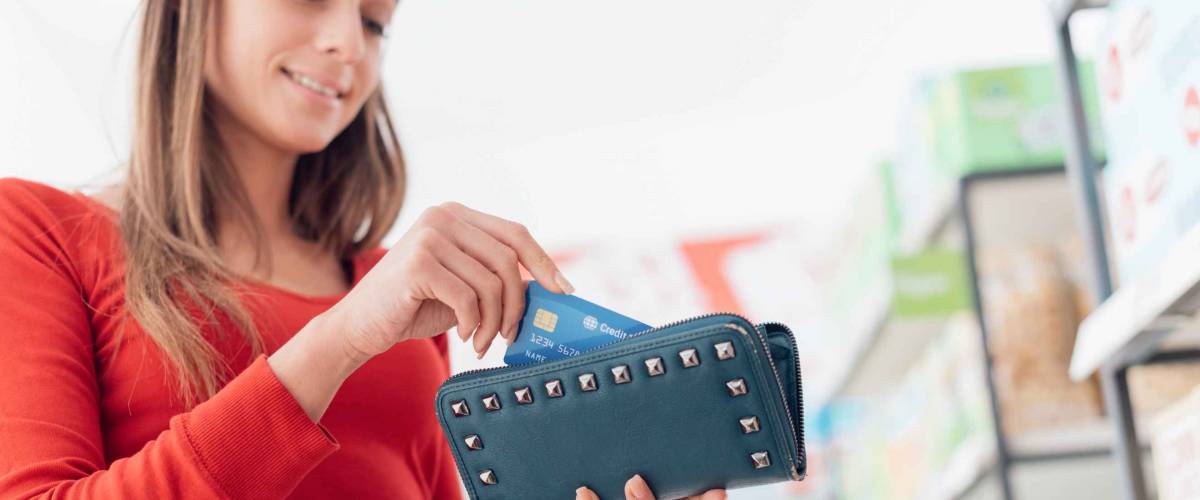 Woman at the supermarket checkout, she is taking a credit card from her wallet, shopping and retail concept