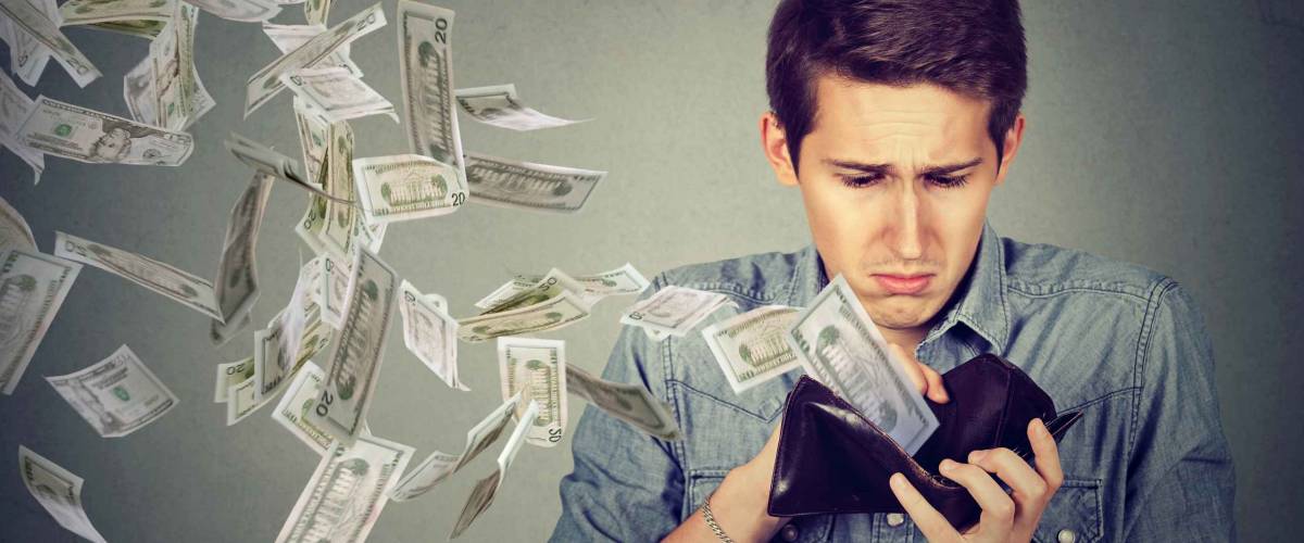 Sad man looking at his wallet with money dollar banknotes flying out away