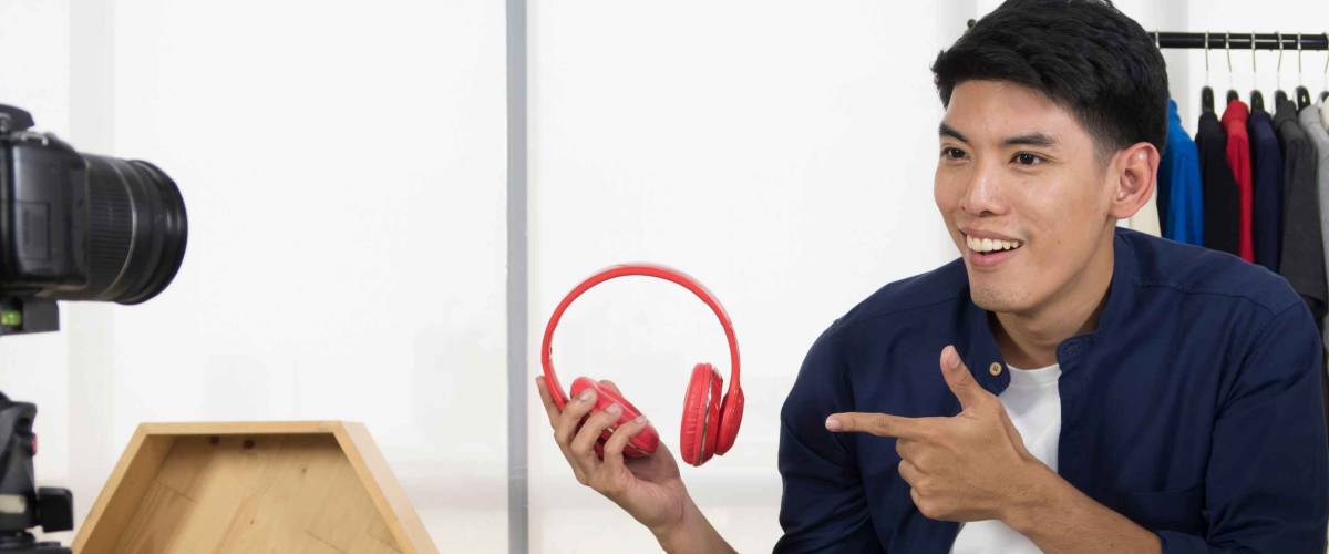 Young man on camera shows off headphones