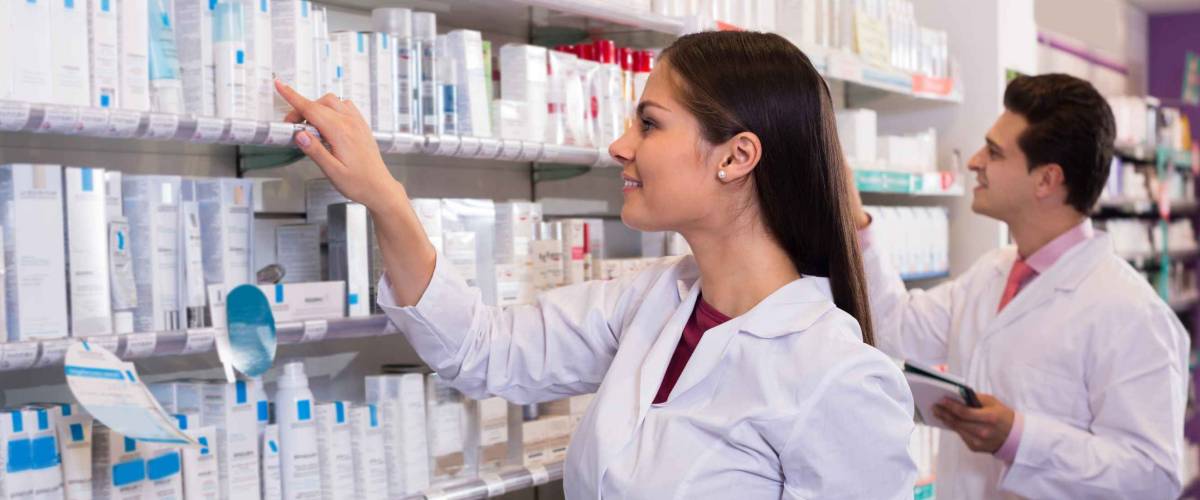 Smiling pharmacist and indian pharmacy technician posing in drugstore