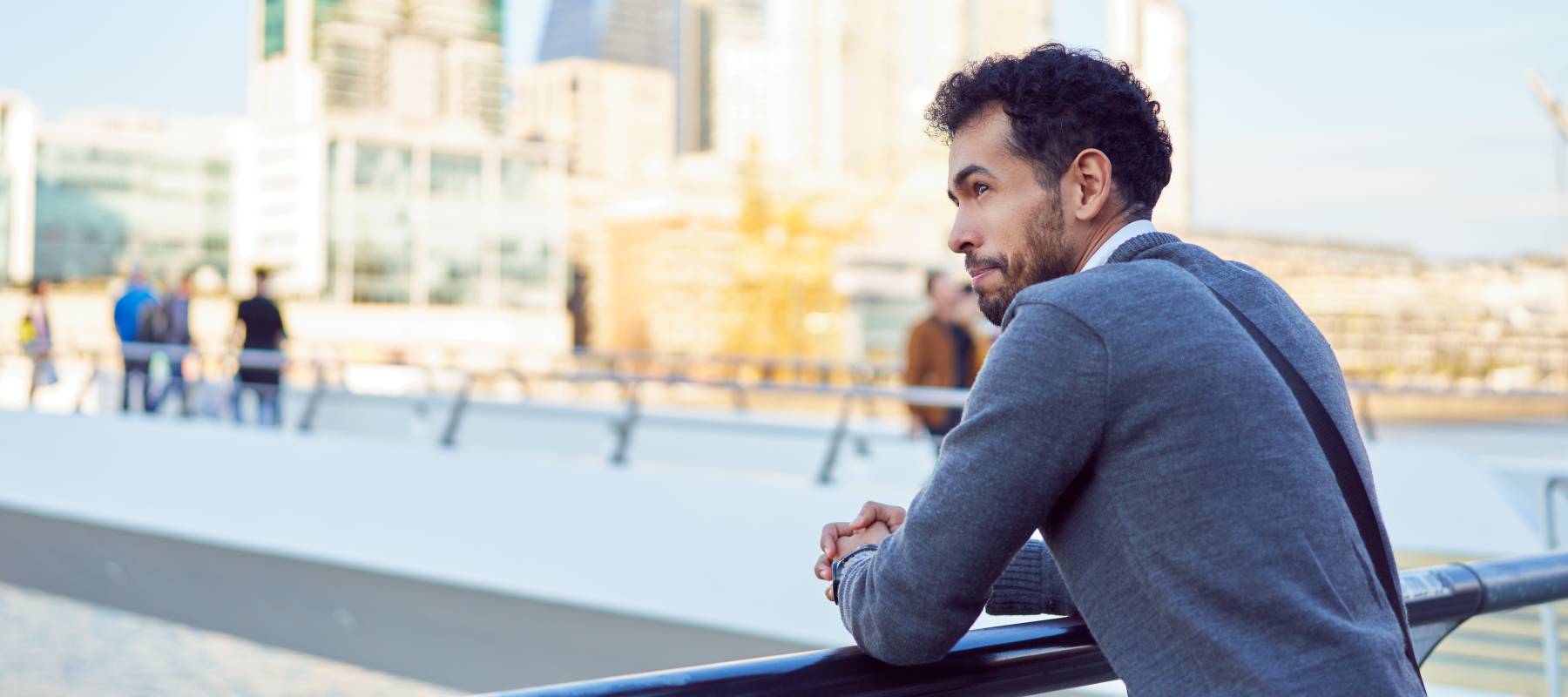 Young man leans on railing outside in city