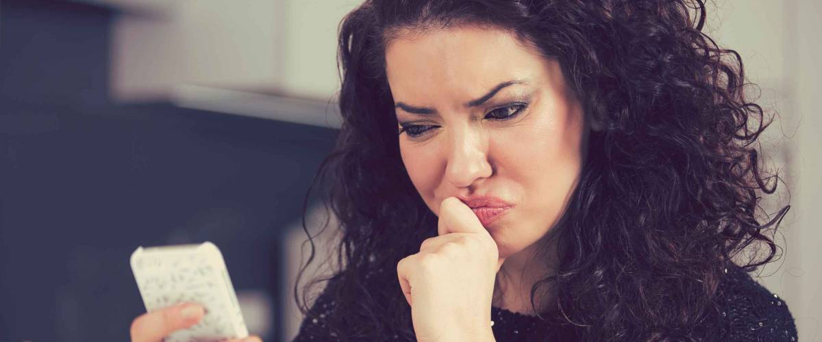 Confused young woman reading text message